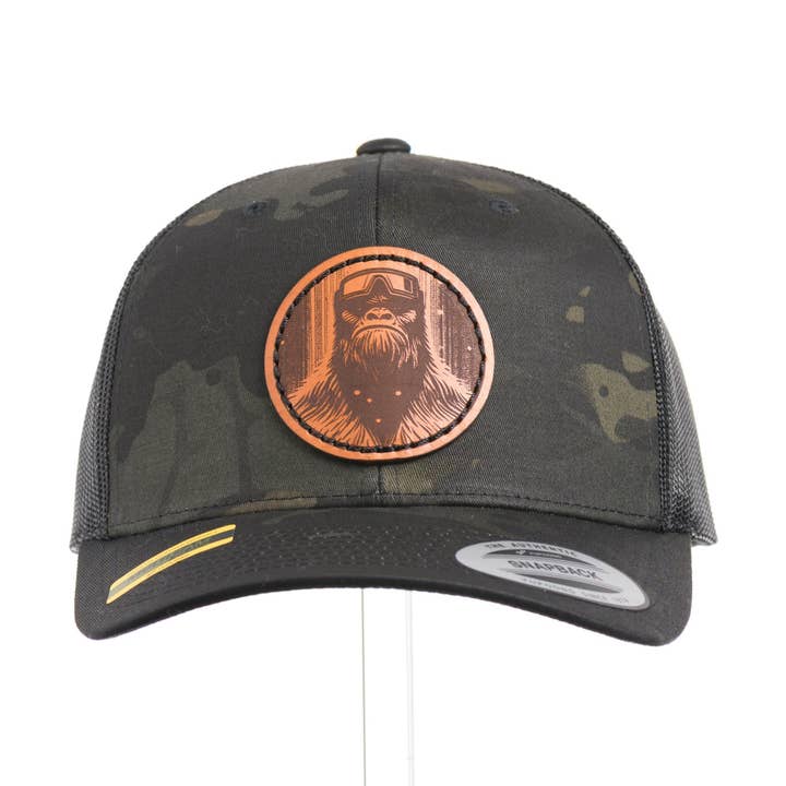 Snowy Bigfoot Leather Patch Black Camo Trucker Hat for wholesale by Last Best Supply Co