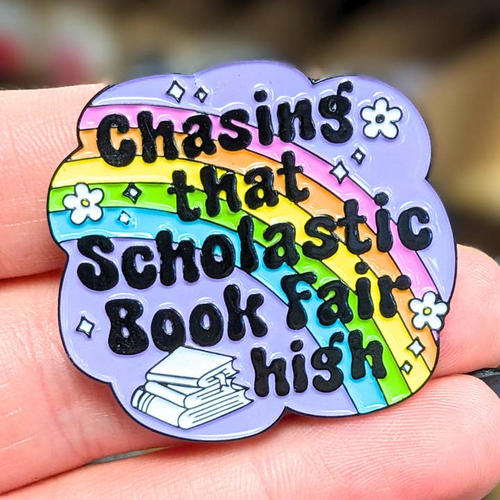Chasing That Scholastic Book Fair High Enamel Pin for wholesale by Indigo Maiden