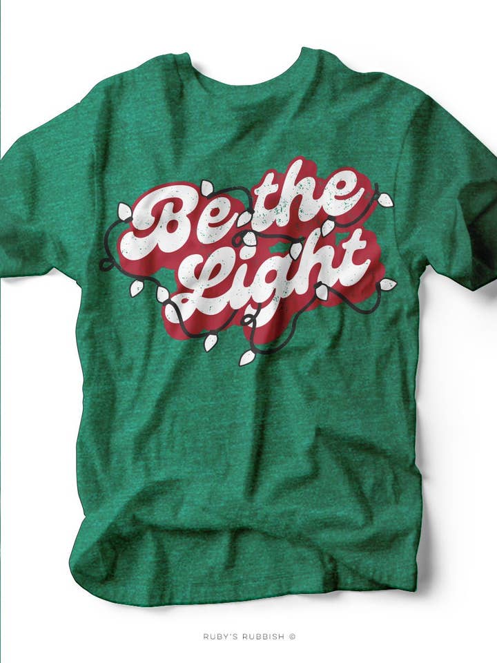 Heather Green Be the Light | Holiday Edition T-Shirt | Ruby’s Rubbish® for wholesale on Faire