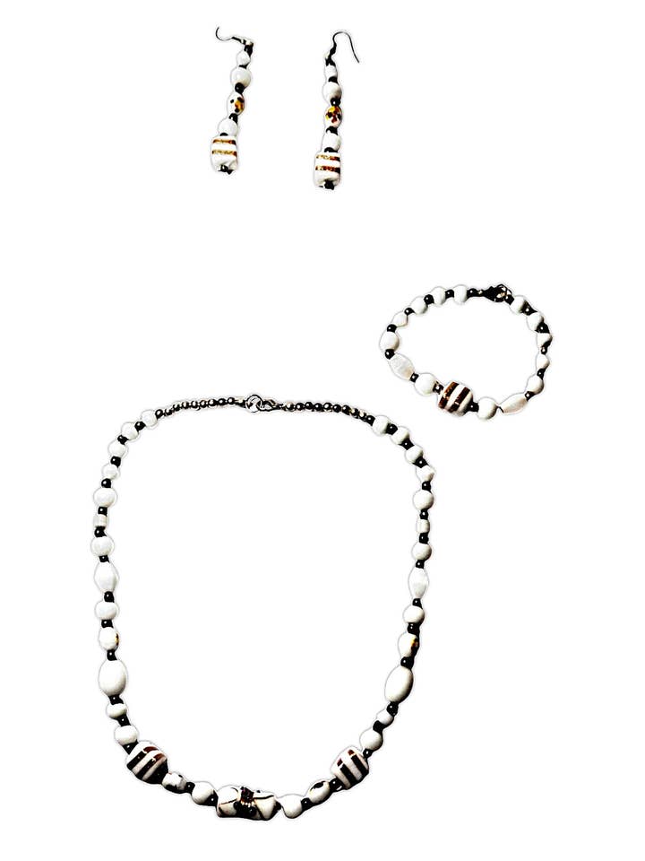 Jewelry set of necklace, bracelet, and earrings in white enameled crystal beads with gold leaf details. for wholesale by Sandra Adrubau