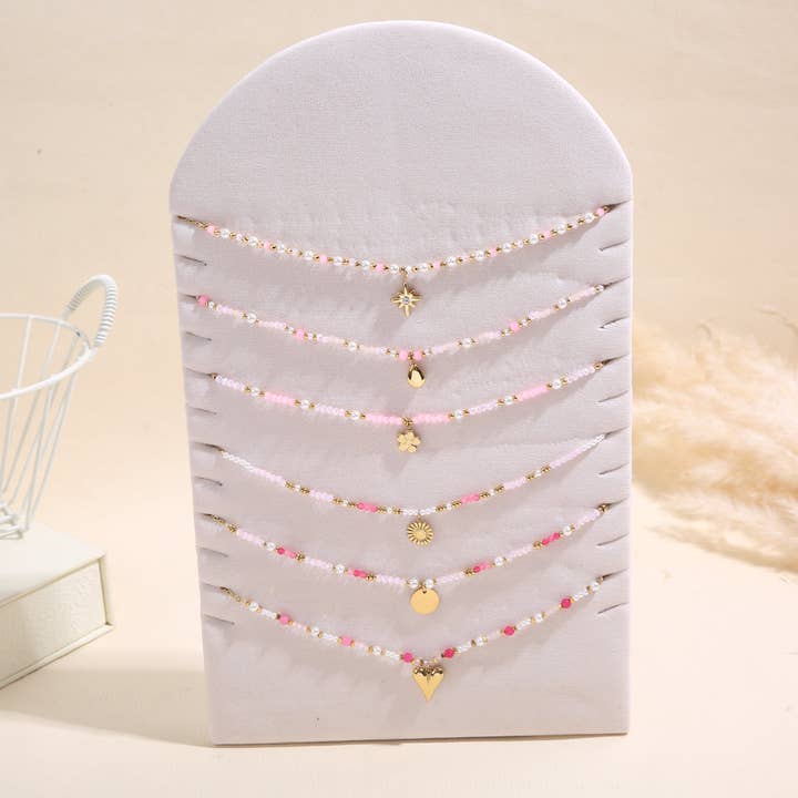 Lot de 6 colliers pendentifs dorés nuances de perles sur présentoir pour la vente par joya