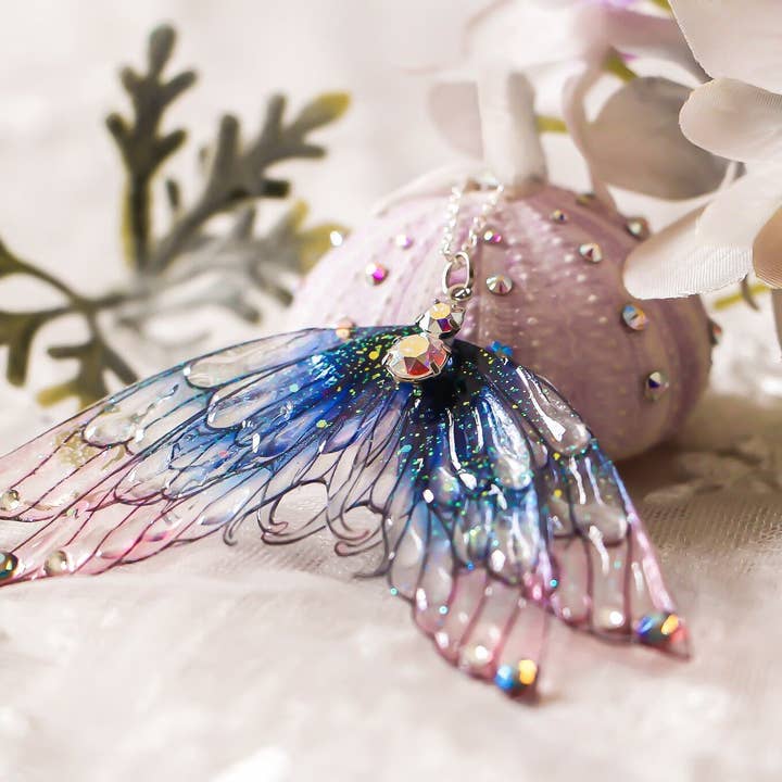 Halskæde med havfruefinne og fire store fevinger i navy blå og pudderrosa for engroshandel hos Faërie