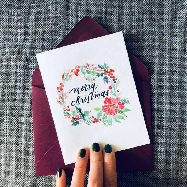 Biglietto di auguri natalizio con ghirlanda ad acquerello "Buon Natale" per la vendita all'ingrosso da parte di Dear Daughters Design