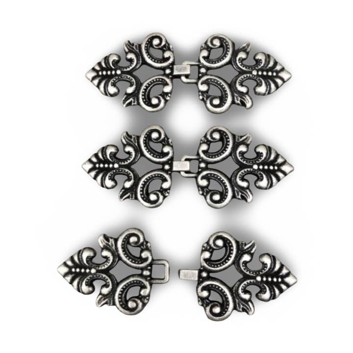 Antique silver flat metal decorative fasteners sew-on 60mmx25mm for wholesale by Hartmann-Knöpfe