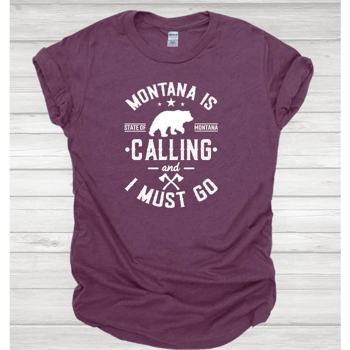 T-shirt Montana Calling I Must Go Gildan per la vendita all'ingrosso da parte di Ink'd Worx by Design