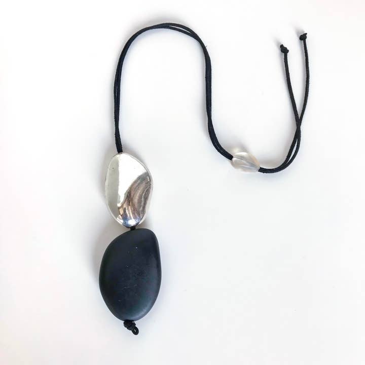 Collana in resina con due ciottoli di fiume (nero e argento) per la vendita all'ingrosso da parte di Belart Fair Trade