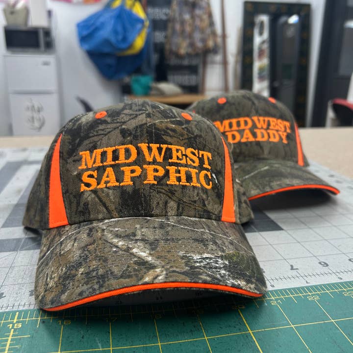 Midwest Sapphic Midwest Daddy Trucker Hat Camo Neon Orange for wholesale by Cottage Lvl Chaos
