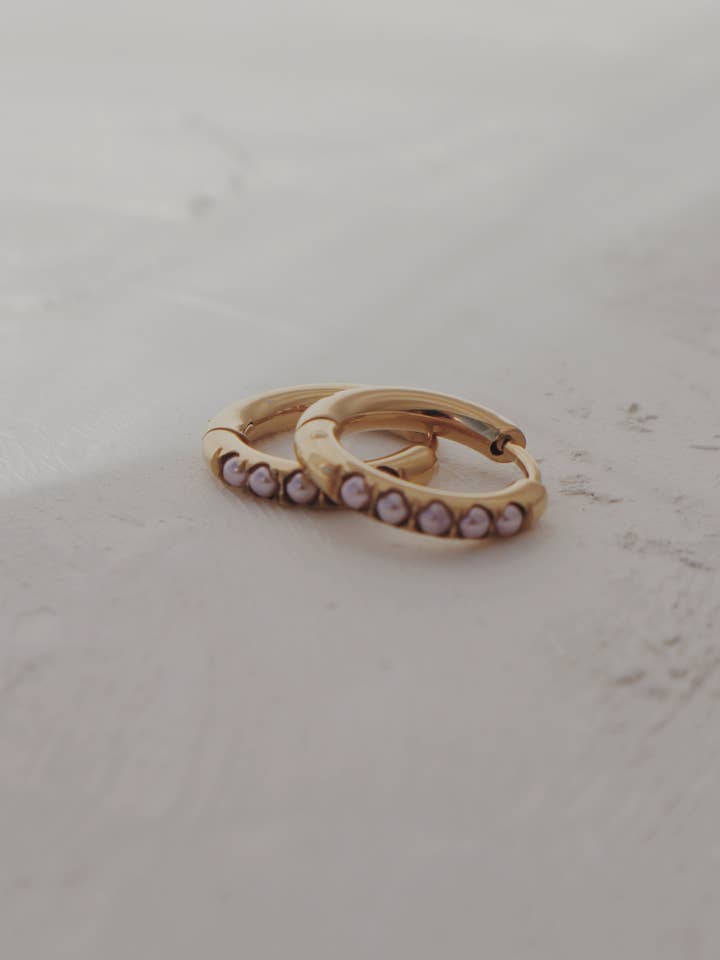 Orecchini a cerchio Glow Huggie in rosa tenue per la vendita all'ingrosso da parte di Olive Branch Jewelry & Co.