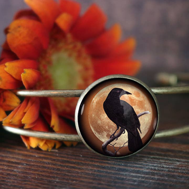 Glazen cabochon-manchetarmband met kraai of raaf op oranje maan voor wholesale door The Divine Iguana
