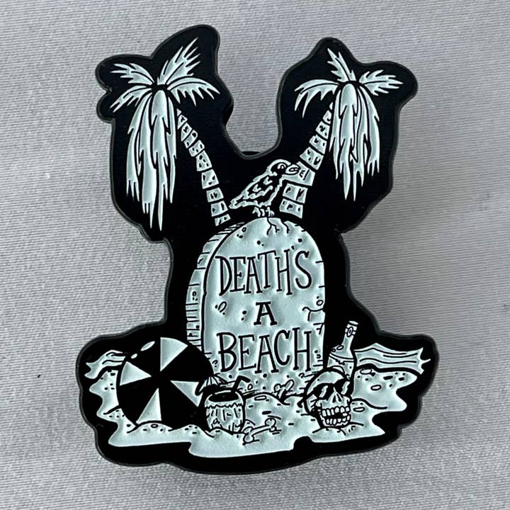 DEATH’S A BEACH 1.75” Glow Goth Horror Soft Enamel Pin for wholesale by The Black Lagoon Room