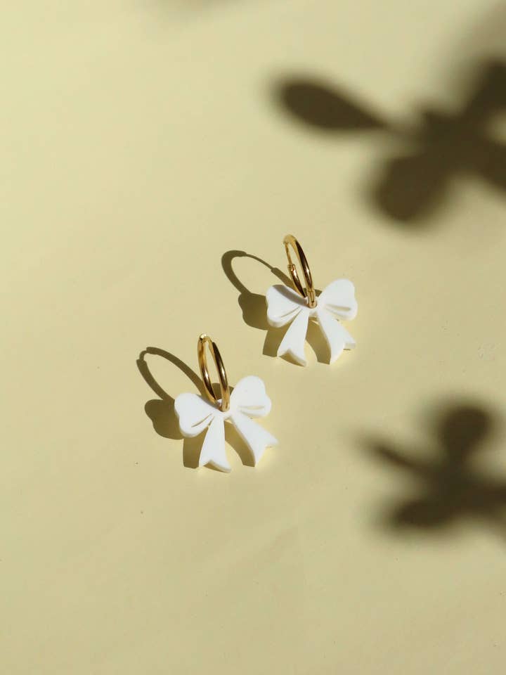 Guldøreringe med hvide sløjfer – legende øreringe med 3D-effekt for engroshandel hos Niemalsmehrohne