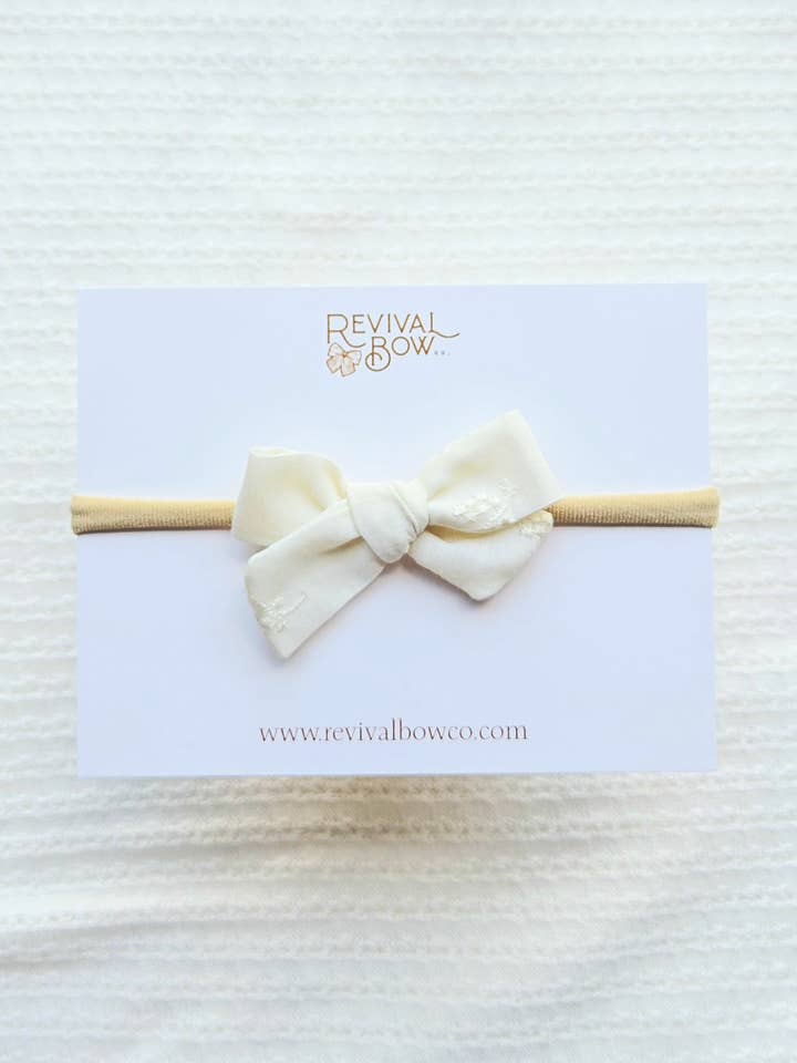 Mini Pinwheel-sløjfe på pandebånd • Elfenbensfarvet broderi anglaise for engroshandel hos Revival Bow Co.