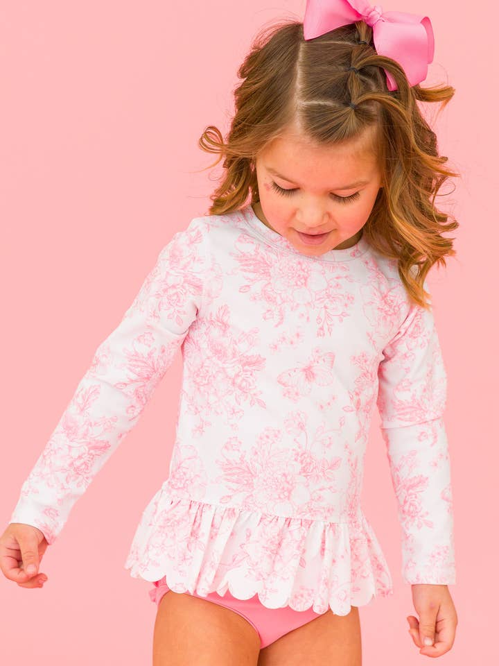 Maillot de bain 2 pièces avec protection anti-UV à manches longues et ourlet festonné, motif jardin de papillons rose chewing-gum pour filles, avec volants signature à l'arrière. pour la vente par RuffleButts + RuggedButts