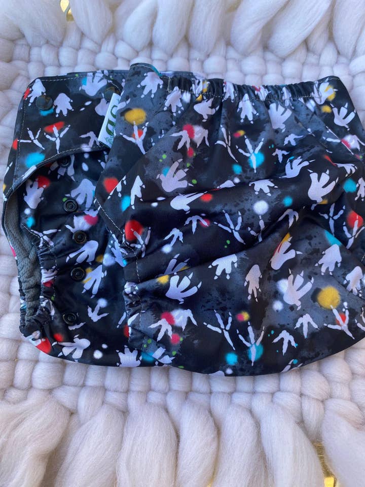 Pannolino in tessuto Dino Splat per la vendita all'ingrosso da parte di Suga Bums LLC