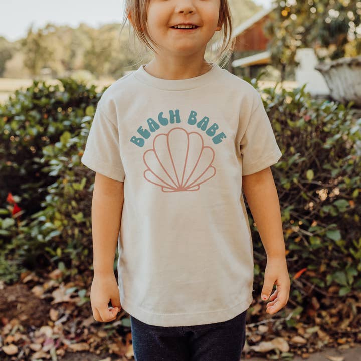 Camiseta estampada retro para niños de Beach Babe, camisa con forma de concha marina para niños pequeños para venta al por mayor de Amber Marie Design