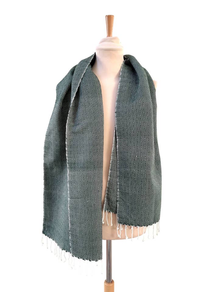 Den varme skovgrønne Krama i sin palmebladskasse - Kvinde for engroshandel hos Krama Heritage