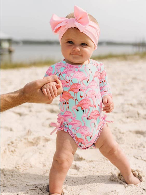Baby meisjes fab flamingo lange mouw eendelig rashguard badpak met kenmerkende ruches aan de achterkant voor wholesale door RuffleButts + RuggedButts