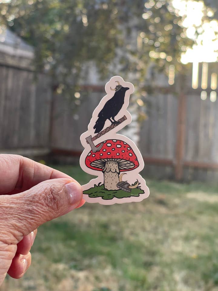Autocollant de champignon Amanite avec hache et corbeau – Décalcomanie en vinyle fantaisiste de champignon rouge de la forêt pour la vente par Color Crumbs Club