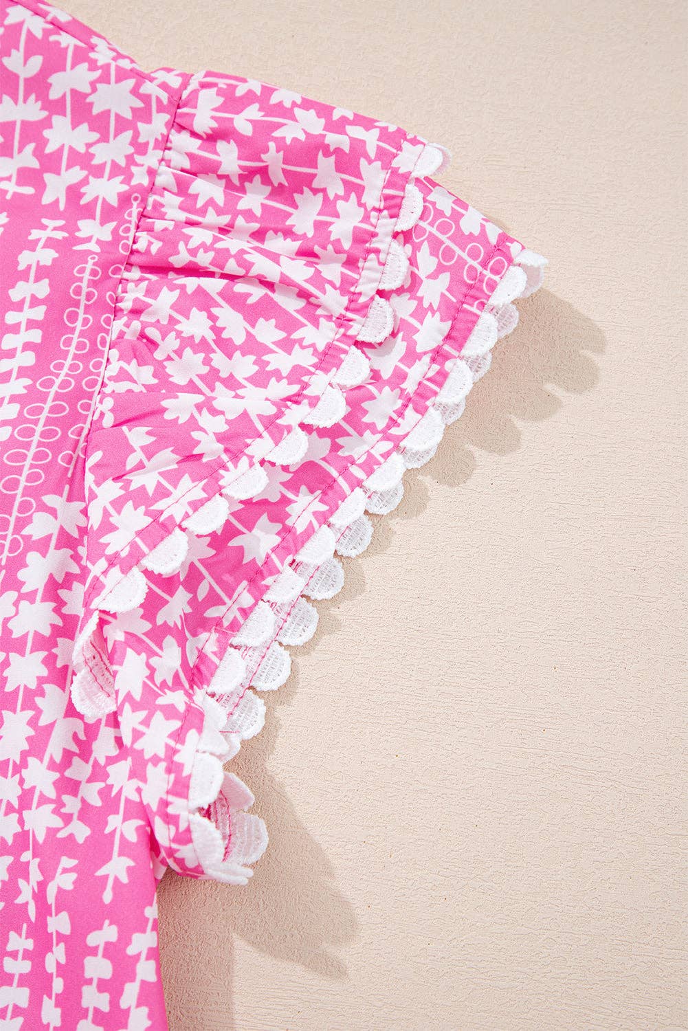 Rosa Blus med abstrakt tryck, ric rac-kant, fladdrande ärmar och V-ringning med skåra. för wholesale på Faire6