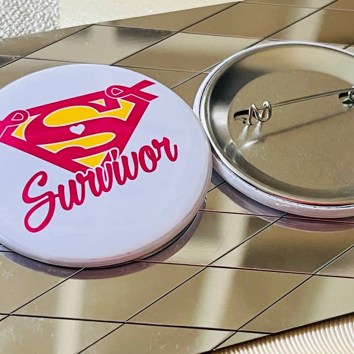 SUPERWOMAN ÜBERLEBENDE - BRUSTKREBSBEWUSSTSEIN 5,7 CM ANSTECKBUTTON für den Großhandel von Stuck On Joy