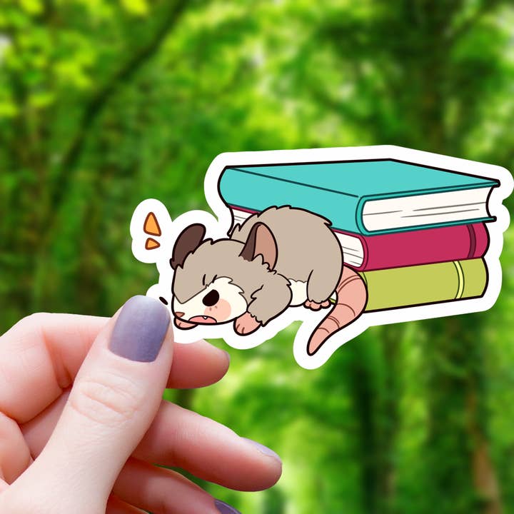 Opossum Guarding Books Sticker- 3" for wholesale by Mimic Gaming Co