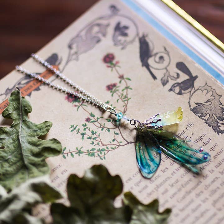 Vedhæng med to alfevinger i grøn og blå gradient for engroshandel hos Faërie