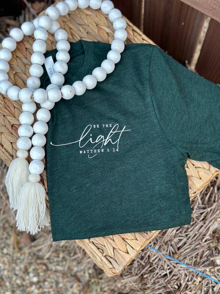 T-shirt grafica da donna Be the Light Emerald Christian per la vendita all'ingrosso da parte di Only Grace Company