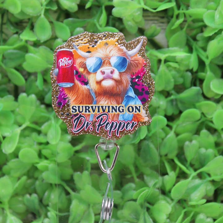 Surviving on Dr Pepper Highland Cow Badge Reel for wholesale by Hylidae Boutique