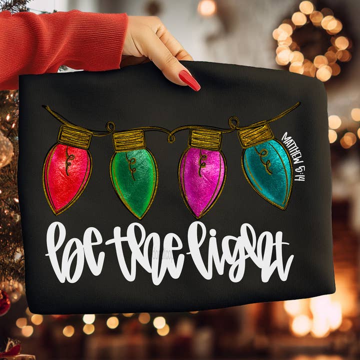 Maglietta Luci di Natale Sii la Luce per la vendita all'ingrosso da parte di Trendy Tee Co.