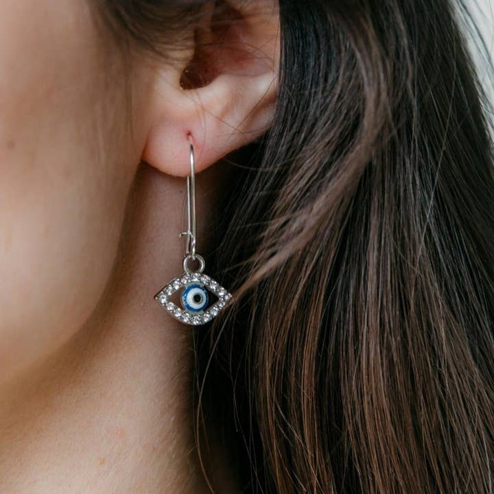 Long Silver Evil Eye Huggie Dainty Zircon Devil Eye Charm Latch Back Earrings for wholesale by The Colourful Aura