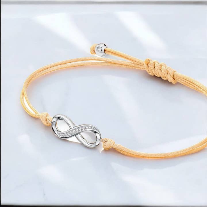 Bracciale "INFINITO" cordoncino beige adattabile Simbolo Infinito argentato per la vendita all'ingrosso da parte di TOURMALYN