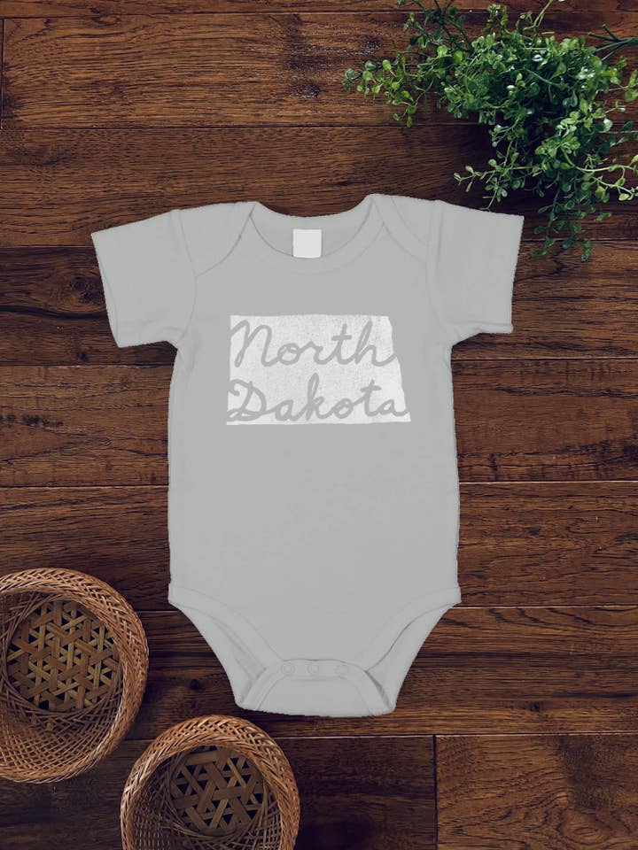 North Dakota Cursive baby-romper tje, witte inkt voor wholesale door Birds Kept North