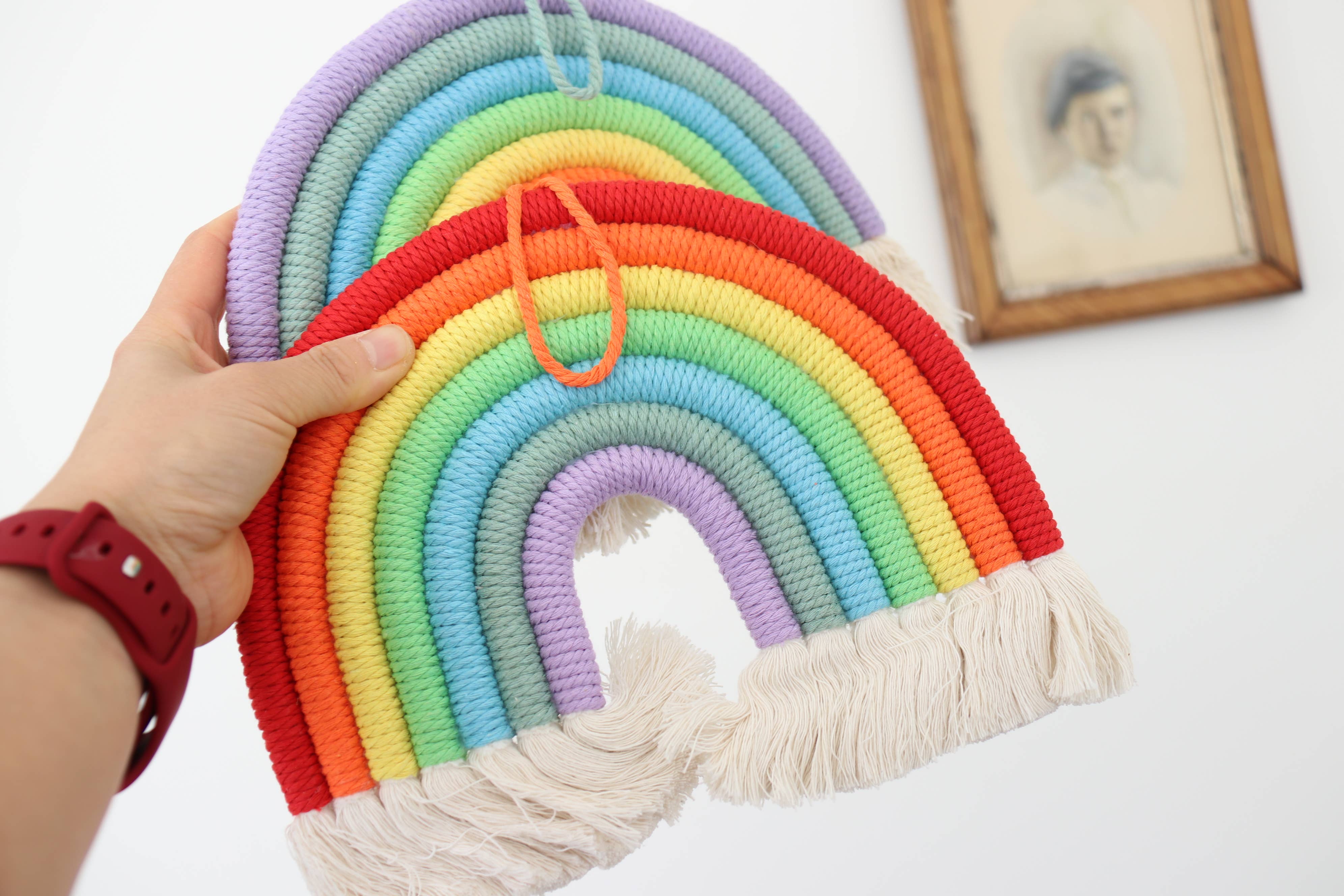 Rosa Decorazione da parete arcobaleno in macramé fatta a mano per cameretta bambini in vendita all'ingrosso su Faire1