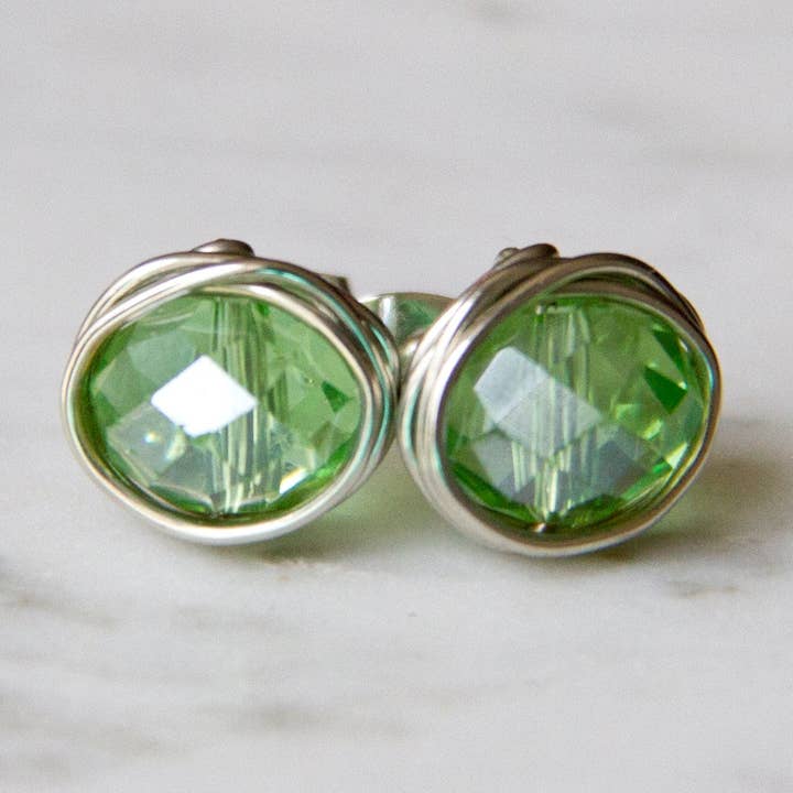 Orecchini a perno avvolti in filo di cristallo cinese verde scintillante, argento, pietra portafortuna di agosto, sfaccettata, con perline per la vendita all'ingrosso da parte di The Jovi Lyne Collection
