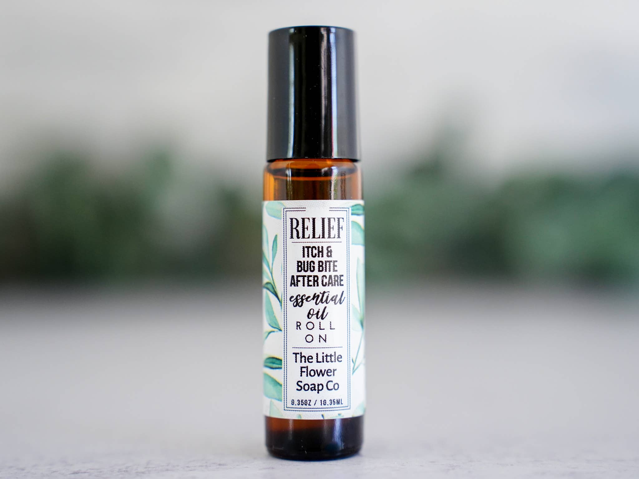 The image showcases a small, dark amber glass roller bottle of “Relief” essential oil blend for after-bite care, labeled 'RELIEF - ITCH & BUG BITE AFTER CARE'.