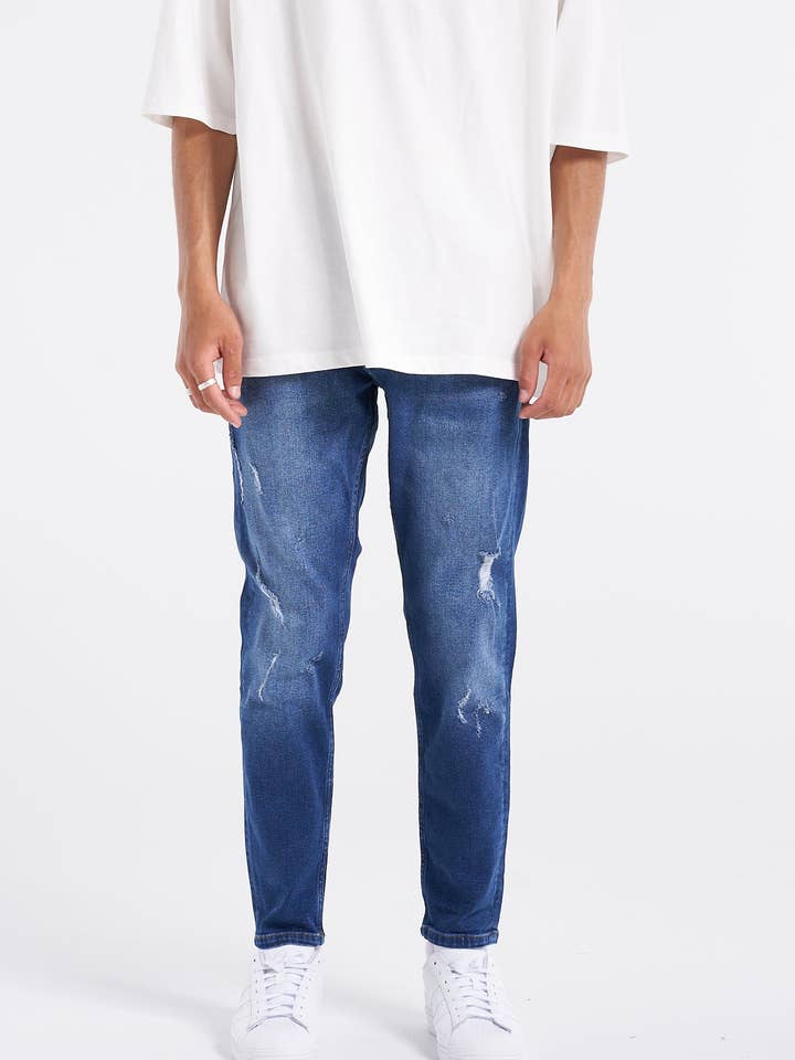 Jean bleu légèrement déchiré de qualité supérieure pour la vente par UNEFFECTED STUDIOS