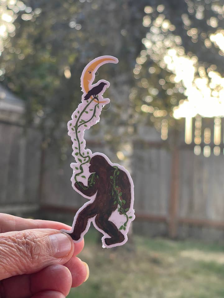 Bigfoot Lasso the Moon Sticker with Crow – Whimsical PNW Vinyl Decal Die Cut Sticker for wholesale by Color Crumbs Club