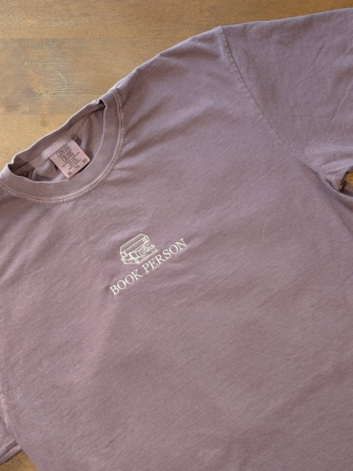 Embroidered Book Person T-Shirt | Comfort Colors Bookish Tee for wholesale by Penelope Annen Design