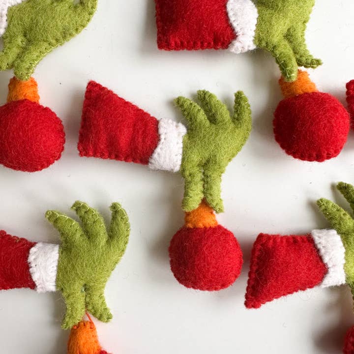 Una mano de fieltro de Grinch que sostiene un adorno para venta al por mayor de Sewing Seeds Play