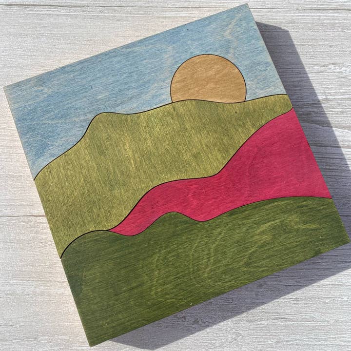 Trævægkunst i lyserød og grøn med bjergmotiv - Rustik solvægdekoration for engroshandel hos Simple and Sylvan