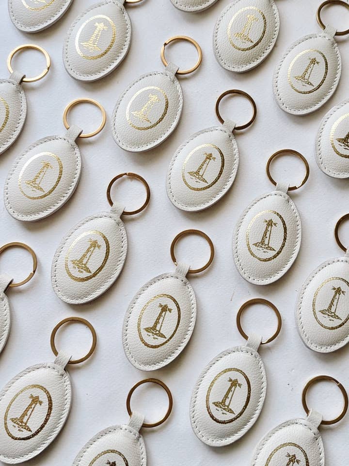 Portachiavi Lighthouse in pelle imbottita – ovale avorio con stampa dorata per la vendita all'ingrosso da parte di Living In Light