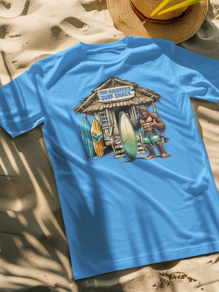 Squatchin’ Country – Großhandel T-Shirt (Grafikdruck) – Unisex – Bigfoot Surf Shack T-Shirt (blau oder gelb) anpassbar1