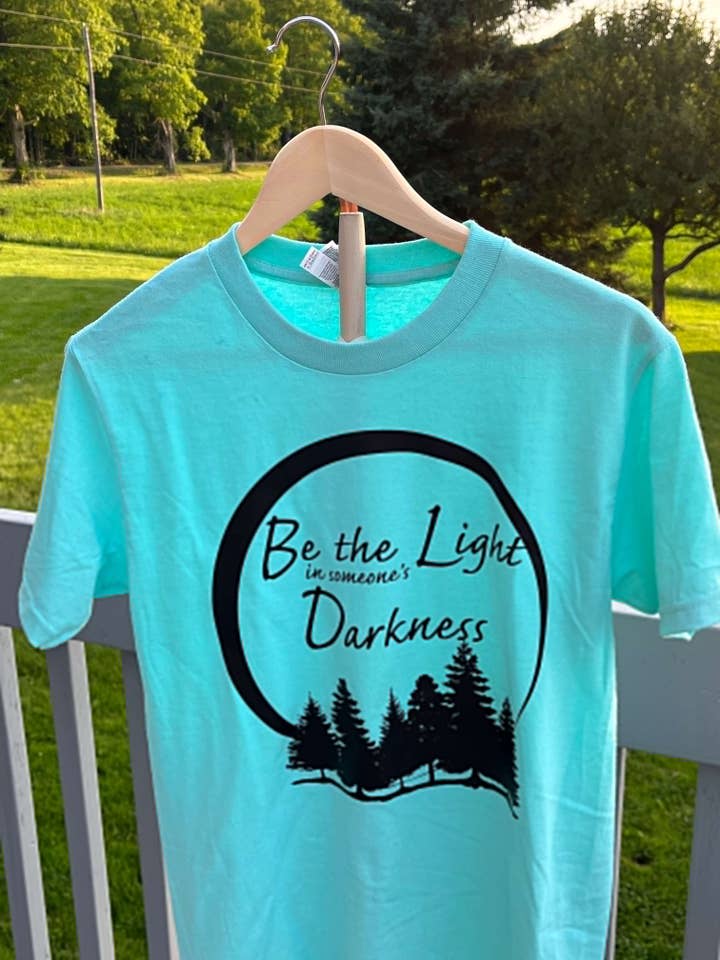 Be the Light in Someone’s Darkness T-Shirt for wholesale by 8 Cool Cats Jewelry Shop
