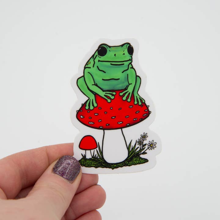 Frog Sitting on a Mushroom Vinyl Sticker for wholesale by Jennifer Schiano Studio
