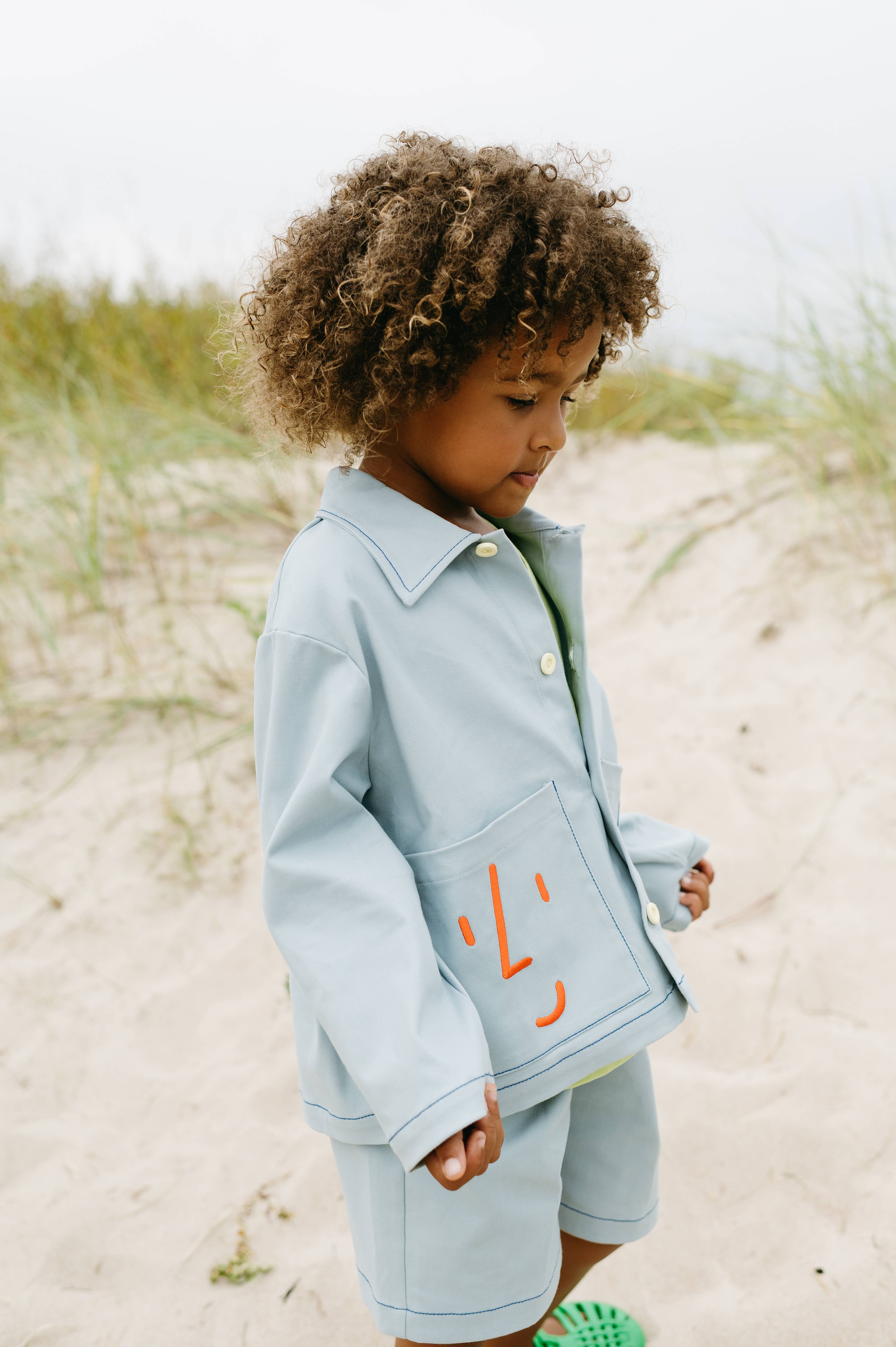 Blauw Utility jas met speelse geborduurde gezichten voor groothandel op Faire5