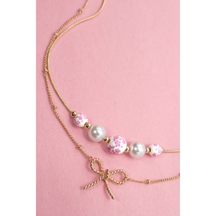 Gold PINK CERAMIC PORCELAIN PEARL BOW LAYER NECKLACE | 80N91556 for wholesale on Faire