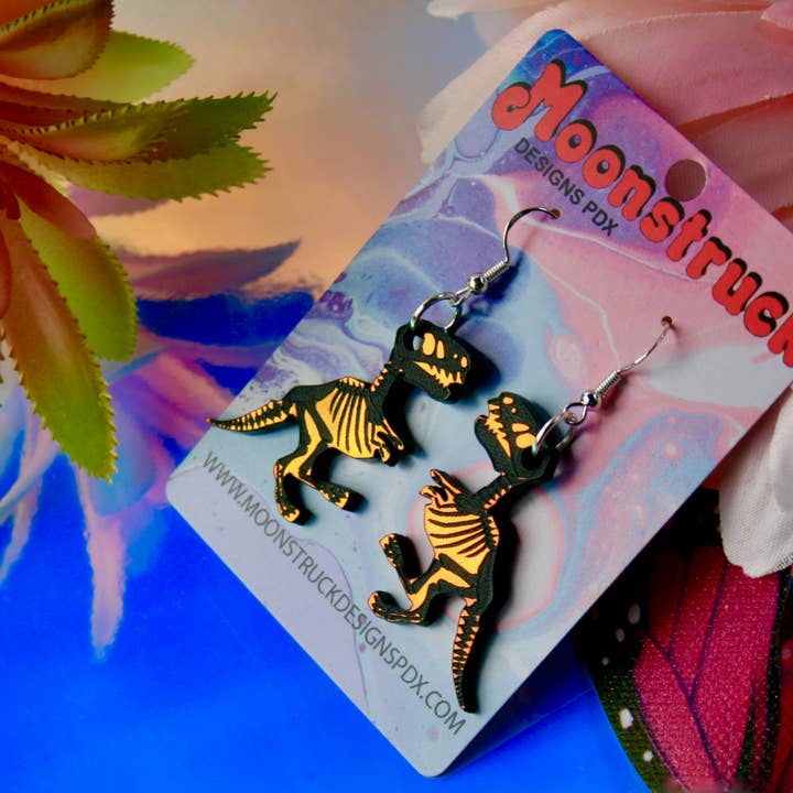 Skelett-Dinosaurier-Ohrringe — Halloween, irisierend, verspiegelt für den Großhandel von Moonstruck Designs PDX