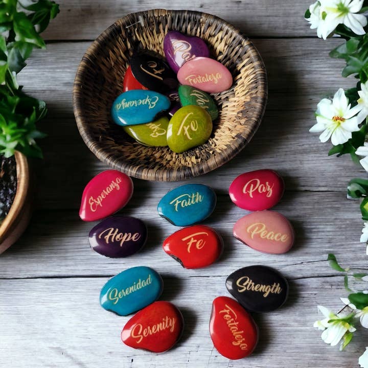Multi Colored Faith engraved riverstones tagua nuts in Spanish for wholesale on Faire
