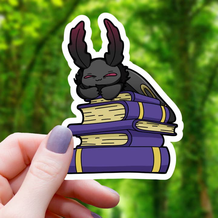 Mothman Sleeping On Pile Of Books Sticker - 3 for wholesale by Mimic Gaming Co