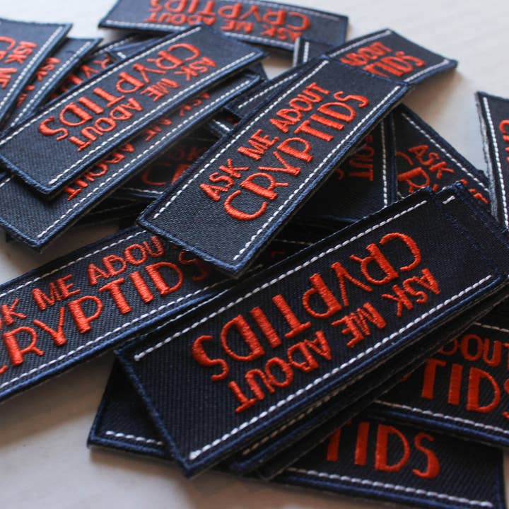 Parche bordado para planchar con mensaje Ask Me About Cryptids de 3" para venta al por mayor de KeikiiArt